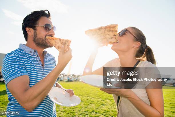 hispanic couple eating pizza slices outdoors - paper plate stock pictures, royalty-free photos & images