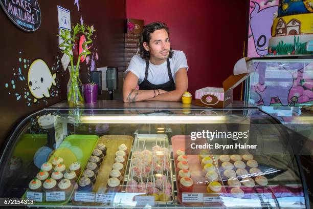 hispanic business owner leaning on bakery display case - cake case stock pictures, royalty-free photos & images