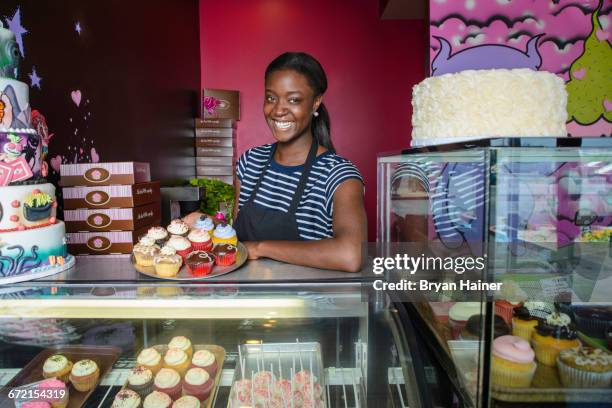 black business owner showing cupcakes at bakery display case - cake case stock pictures, royalty-free photos & images