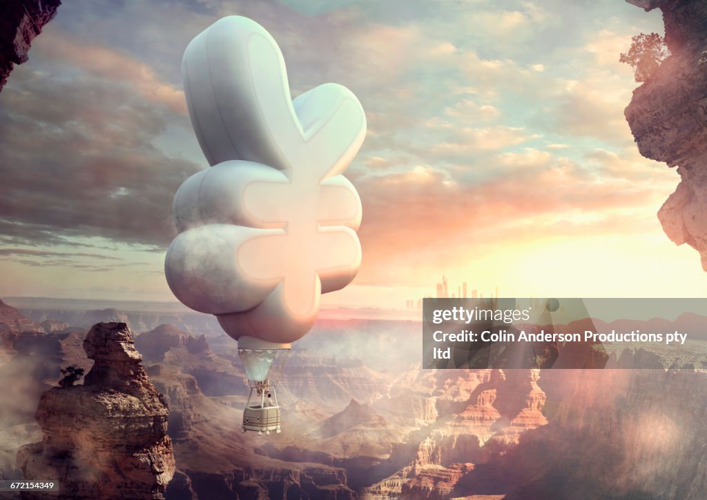 Mixed Race man floating in yuan hot air balloon at sunset