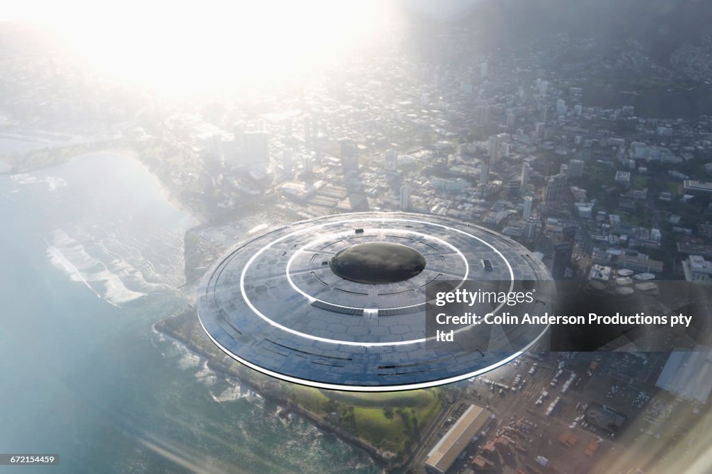 Circular UFO flying over city