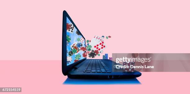 playing cards and gambling chips emerging from laptop screen - jogos de azar imagens e fotografias de stock