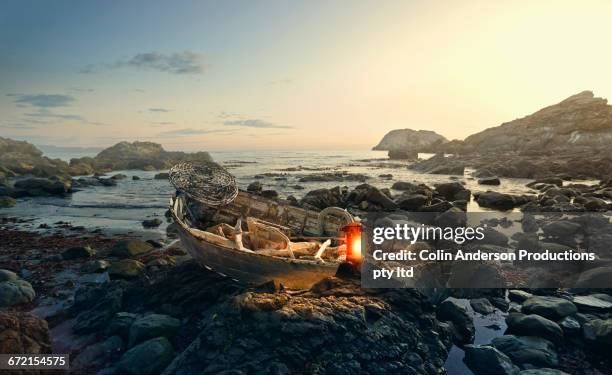 lantern glowing on rowboat at rocky shore - greymouth stock-fotos und bilder