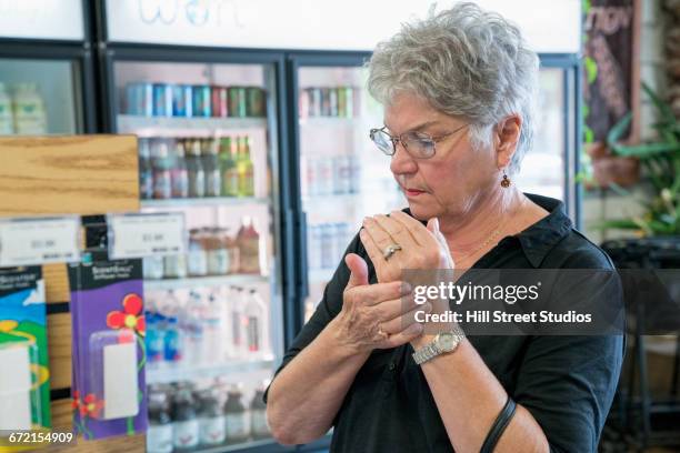 caucasian woman sampling lotion in nutrition store - qual der wahl stock-fotos und bilder