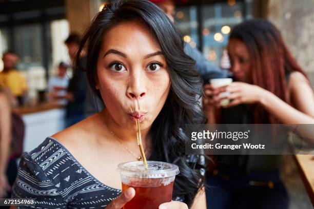 woman drinking cold drink with straw in cafe - pajita fotografías e imágenes de stock