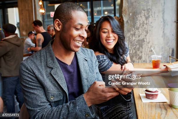 couple using cell phone in cafe - african american restaurant texting stockfoto's en -beelden