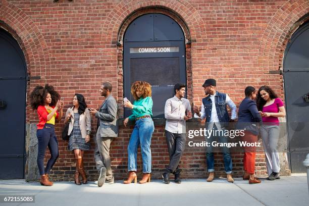 people waiting in line at theater using cell phones - line up stockfoto's en -beelden