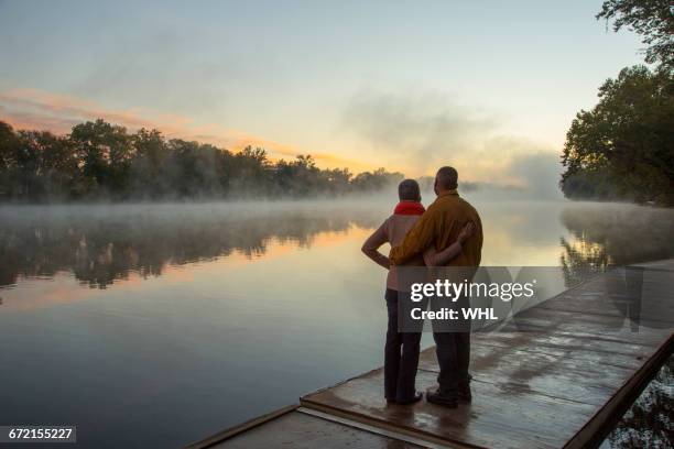 older couple hugging at foggy river at sunrise - black woman looking at view stock pictures, royalty-free photos & images