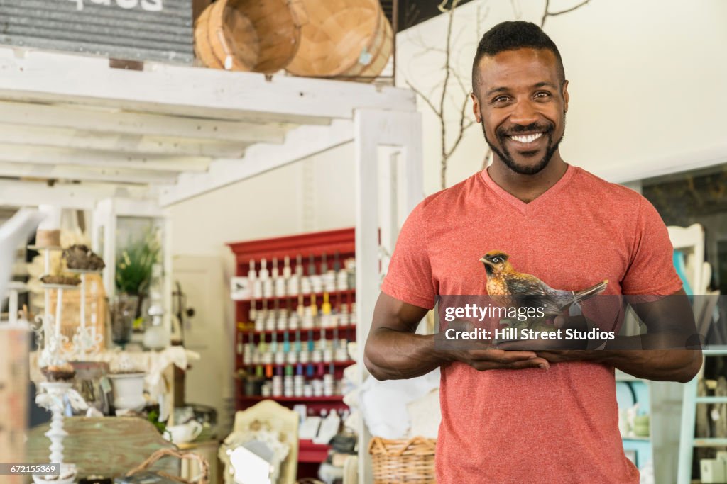 Black man holding bird statue in antique store