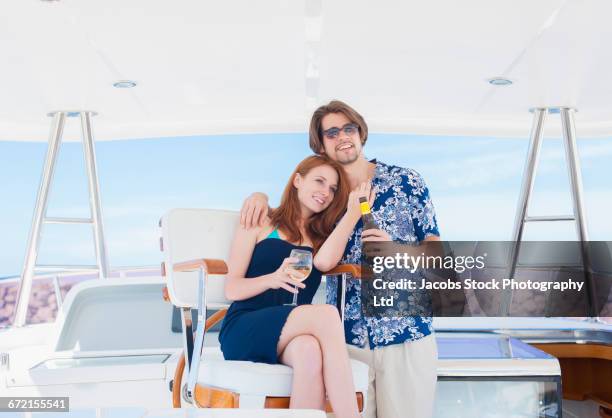 smiling couple hugging on boat drinking beer and wine - wine bottle transport stock pictures, royalty-free photos & images