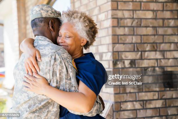 black soldier hugging wife on front stoop - homecoming stock pictures, royalty-free photos & images