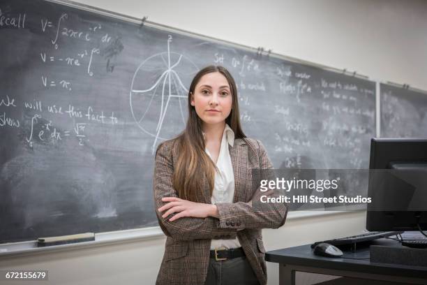 caucasian woman with arms crossed in classroom - blackboard classroom stock-fotos und bilder