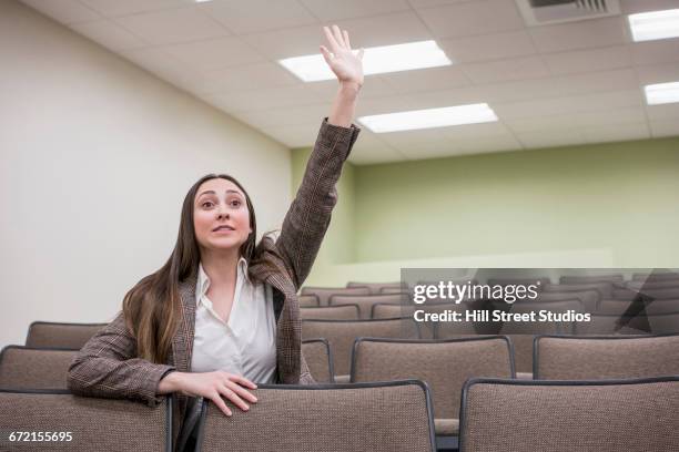caucasian woman raising hand in classroom - hand raised stock pictures, royalty-free photos & images