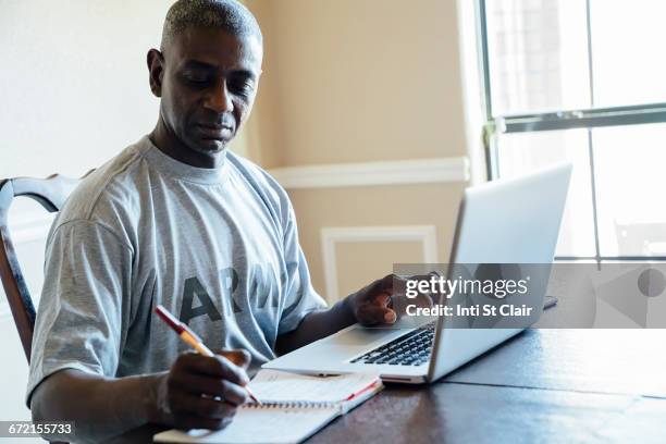Black Man Using Laptop And Notebook At Table, 照片檔