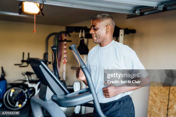 black man running on treadmill in garage - one man only studio stock pictures, royalty-free photos & images