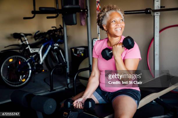 black woman lifting weights in garage - lifting weights stock-fotos und bilder