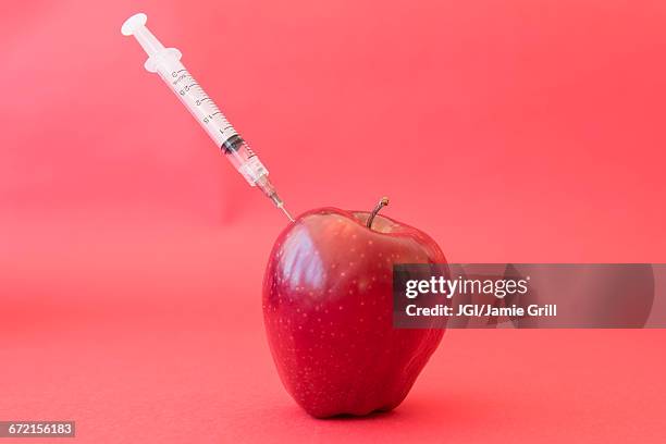 syringe injecting red apple - genetically modified food stock pictures, royalty-free photos & images