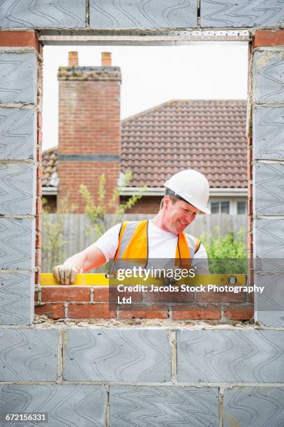 caucasian construction worker using level to check brick wall - spalding place bildbanksfoton och bilder