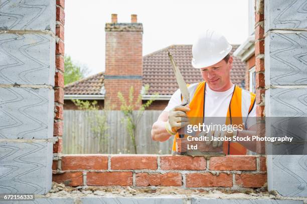 caucasian construction worker laying bricks with mortar - brick layer bildbanksfoton och bilder