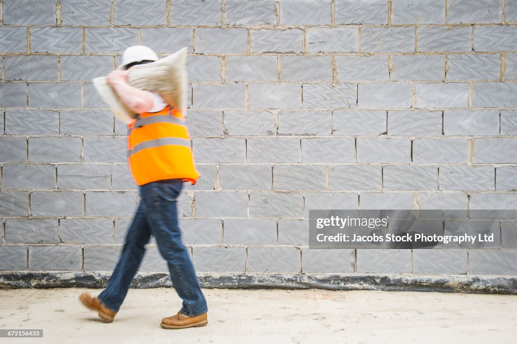 Caucasian construction worker carrying sack