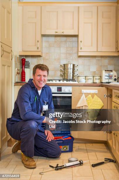 caucasian plumber kneeling on kitchen floor with tools - spalding place bildbanksfoton och bilder
