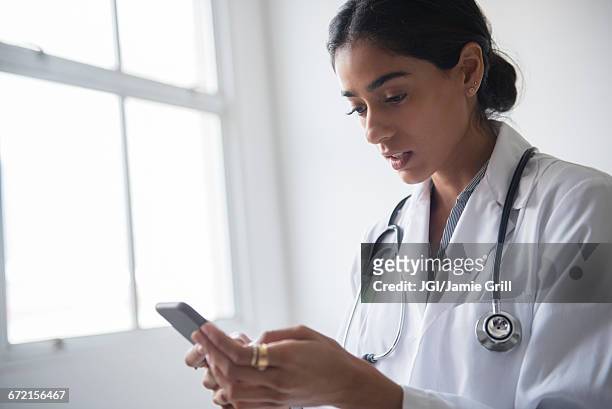 indian doctor texting on cell phone - doctor smartphone stock pictures, royalty-free photos & images