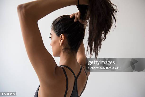 indian woman putting hair in ponytail - ponytail hairstyle stock pictures, royalty-free photos & images