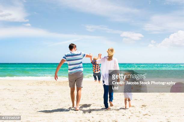 caucasian family swinging son by arms at beach - family holidays australia stock-fotos und bilder