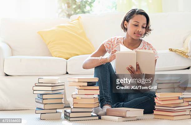 black woman sitting on floor reading pile of books - black book ストックフォトと画像