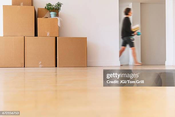 woman walking near cardboard boxes stacked against wall - loan process stock pictures, royalty-free photos & images