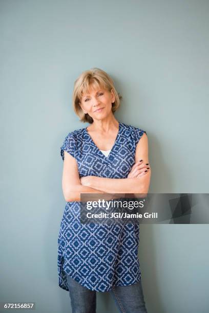 confident older caucasian woman standing at wall - tuniek stockfoto's en -beelden