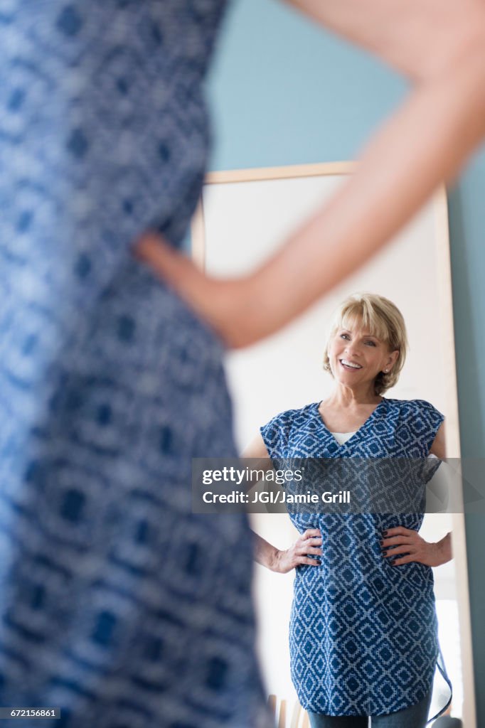 Older Caucasian woman admiring dress in mirror