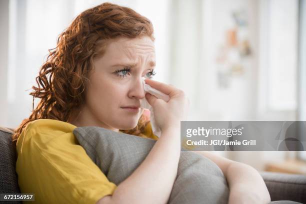 crying caucasian woman clutching pillow wiping tears - teardrop stockfoto's en -beelden