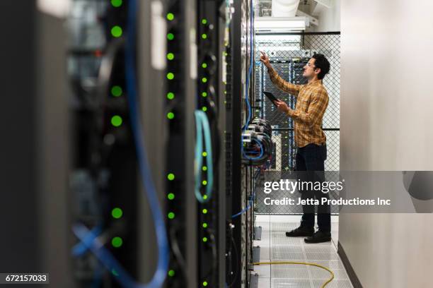 hispanic technician working in computer server room - computer cable foto e immagini stock