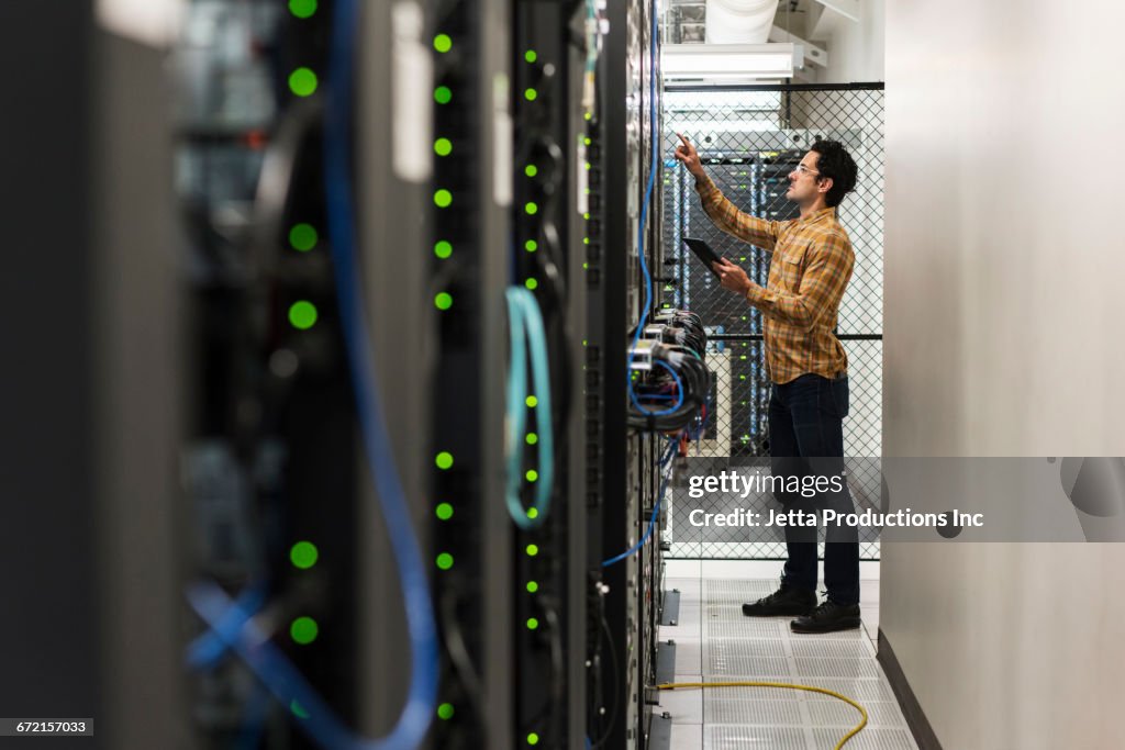 Hispanic technician working in computer server room