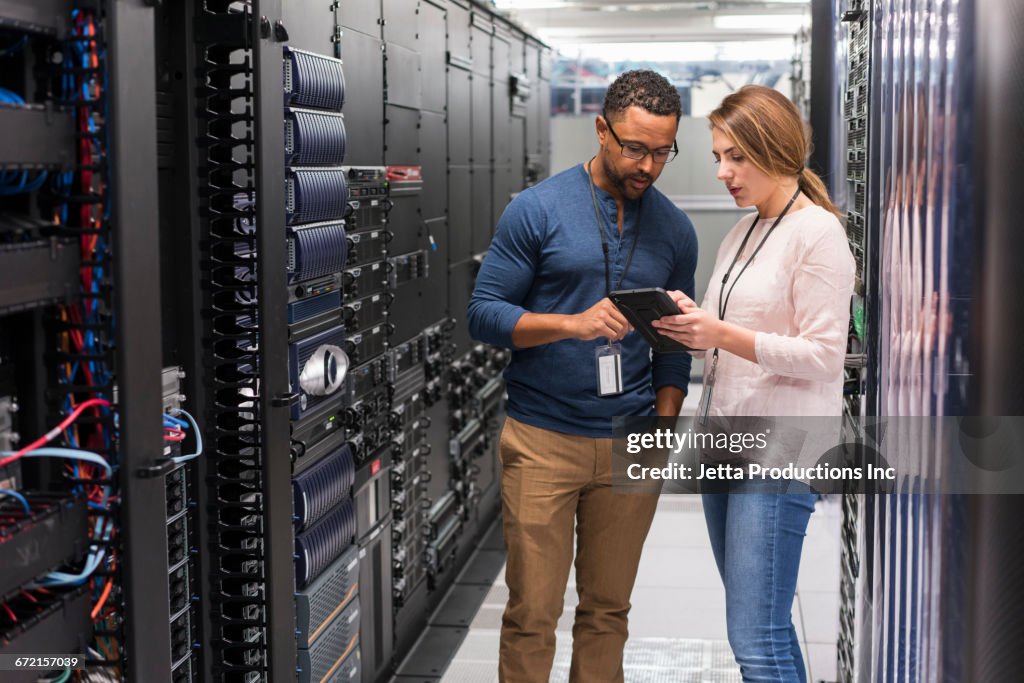 Technicians using digital tablet in computer server room