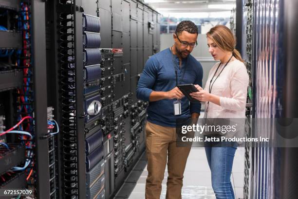 technicians using digital tablet in computer server room - großrechner stock-fotos und bilder