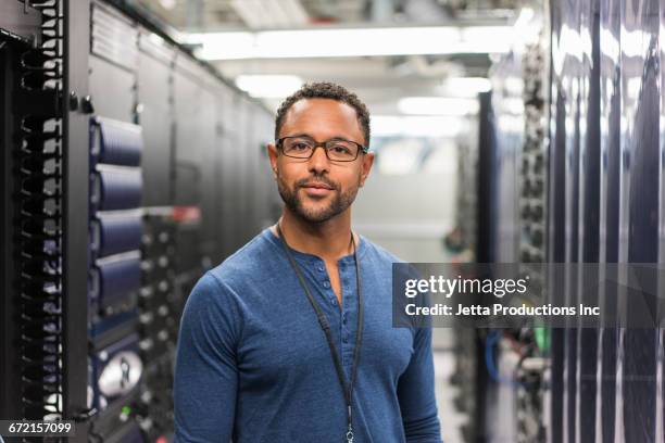 mixed race technician posing in computer server room - technicus stockfoto's en -beelden