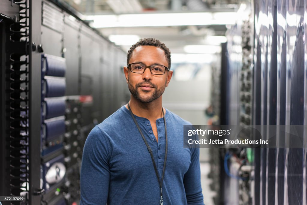 Mixed Race technician posing in computer server room