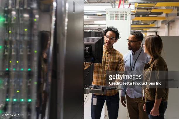 technicians using computer in server room - diversidad cultural fotografías e imágenes de stock