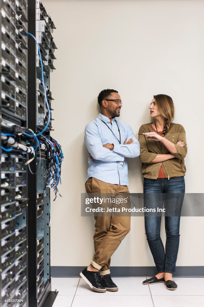 Technicians leaning on wall talking in computer server room