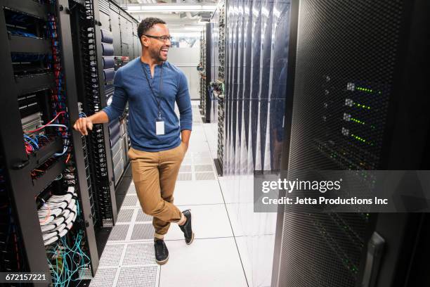 mixed race technician laughing in computer server room - cordel acreditativo fotografías e imágenes de stock