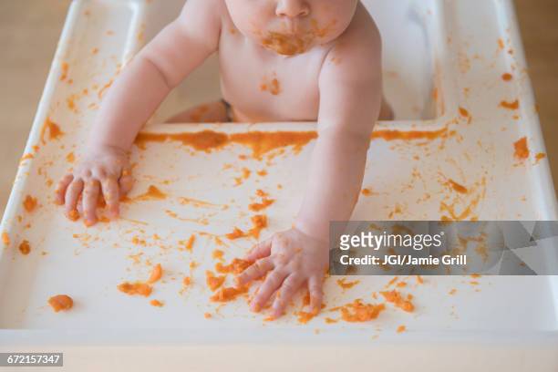 caucasian baby girl self-feeding mashed sweet potato - mashed sweet potato stock pictures, royalty-free photos & images