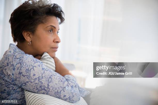 pensive older black woman clutching pillow - woman concerned stockfoto's en -beelden