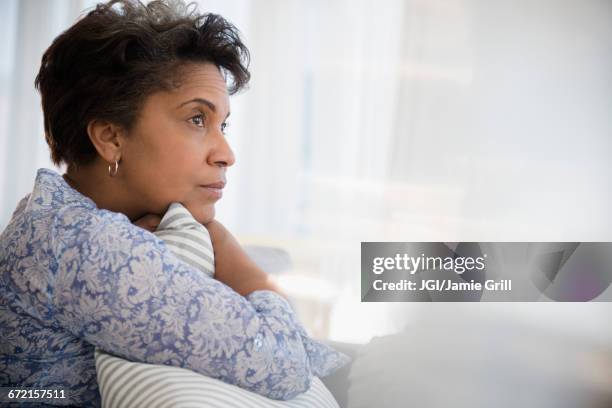 pensive older black woman clutching pillow - woman concerned stock pictures, royalty-free photos & images