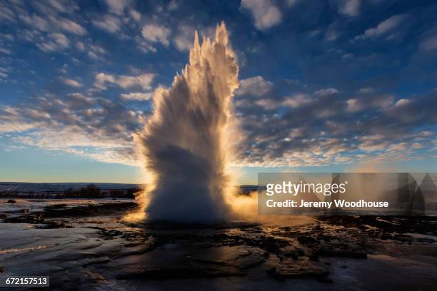 geyser erupting at sunrise - geysir stock-fotos und bilder