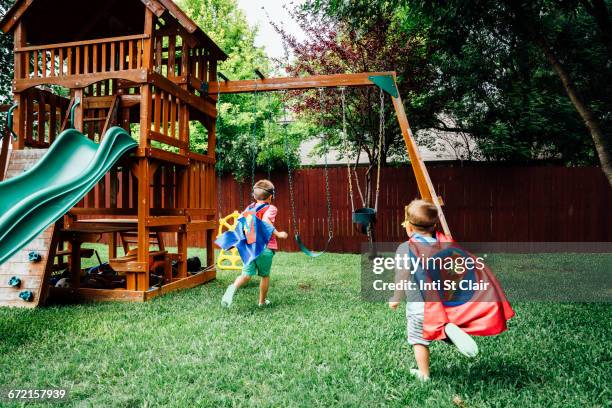 brothers wearing superhero costumes in backyard - rutsche stock-fotos und bilder