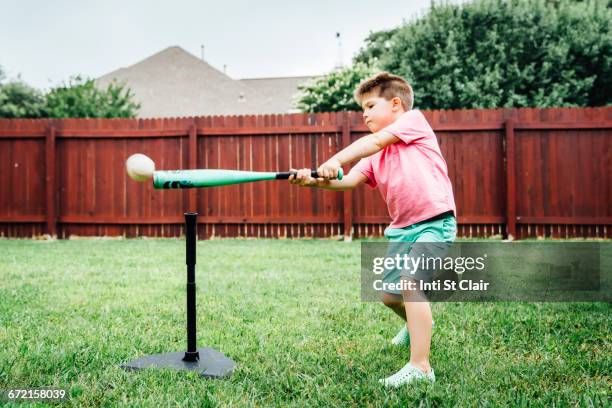 caucasian boy hitting baseball off tee in backyard - backyard baseball stock pictures, royalty-free photos & images