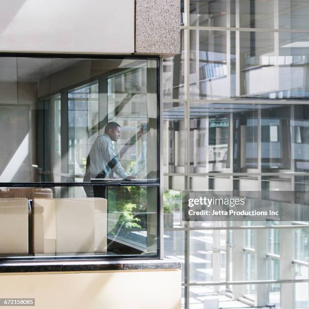 black businessman looking out window of corner office - corner office stock pictures, royalty-free photos & images