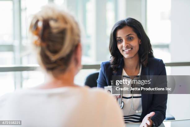 doctor talking with patient in office - boss over shoulder stock-fotos und bilder